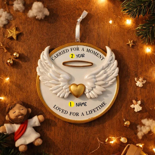 Decorative angel wings ornament with customizable text on a wooden background with Christmas decorations.