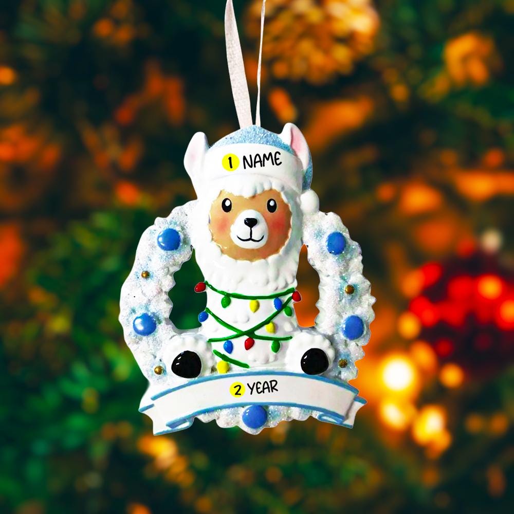 Personalized baby boy llama ornament featuring a cute smiling llama wearing a winter hat and surrounded by a festive wreath with colorful holiday lights. Soft blue and white tones create a cozy winter look. Handwritten personalization includes baby name and Baby’s First Christmas with year. Mostly 2D ornament with raised 3D details on the front only, lightweight and perfect for Christmas trees, nursery decor, and baby keepsakes.