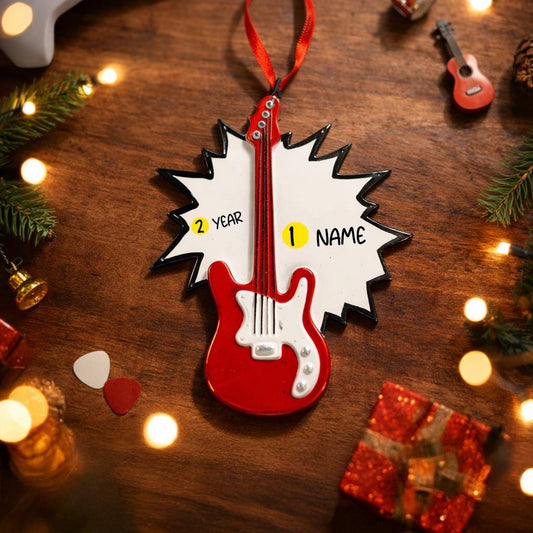 Red guitar-shaped ornament with customizable text on a wooden surface with festive decorations.