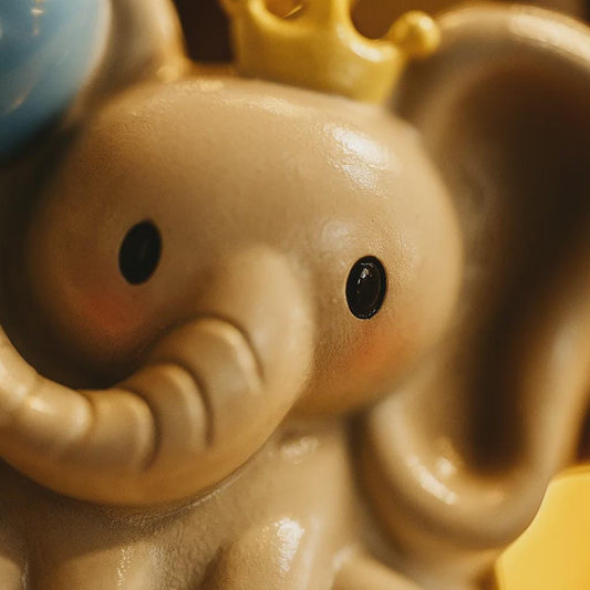 Close-up of a toy elephant with a blue hat and yellow crown.