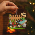 Load image into Gallery viewer, Personalized gardener ornament featuring a detailed garden scene with wooden fence wheelbarrow potted plants gardening tools and soil elements. The design includes a customizable name on the fence and a year on the base making it a thoughtful keepsake for garden lovers. The ornament has a warm rustic farmhouse style and is displayed with a red hanging ribbon suitable for Christmas trees seasonal decor and gift displays.
