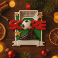 Load image into Gallery viewer, Christmas ornament with soccer ball, goal, and 'SCORE' text on a wooden background with decorations.
