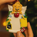 Load image into Gallery viewer, Decorative teacher angel ornament with educational items held by a hand against a blurred background.
