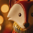 Load image into Gallery viewer, Close-up of a ceramic fox figurine with a checkered scarf against a blurred warm light background
