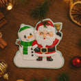 Load image into Gallery viewer, Personalized Santa and snowman ornament featuring a classic Christmas design with Santa holding a bell and a smiling snowman standing beside him. The ornament includes custom name and year personalization on the figures and base. Finished with a smooth glossy surface and detailed 3D front, it is designed for easy hanging on a Christmas tree. Perfect for festive holiday decor, family keepsakes, and seasonal gift giving.
