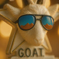 Load image into Gallery viewer, Decorative figurine of a goat wearing sunglasses with 'G.O.A.I.' text on a warm-toned background
