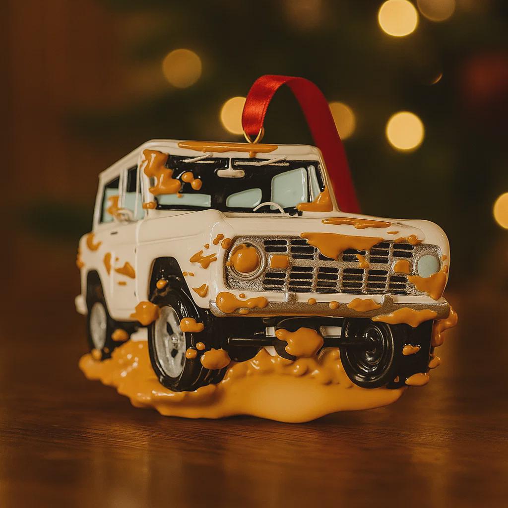 Decorative Christmas ornament shaped like a truck with a red ribbon on a wooden surface.