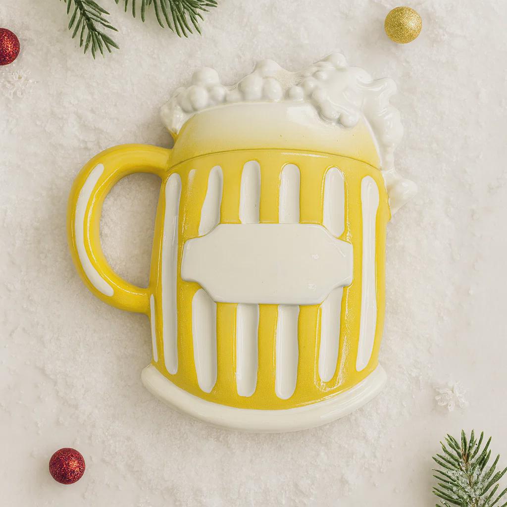 Yellow mug with white handle and design, surrounded by Christmas decorations on a light background