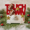Load image into Gallery viewer, Decorative Christmas ornament with 'Touchdown' text, footballs, and a helmet on a snowy background.
