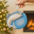 Load image into Gallery viewer, Decorative ornament with Trout fish design held by a hand against a festive background.
