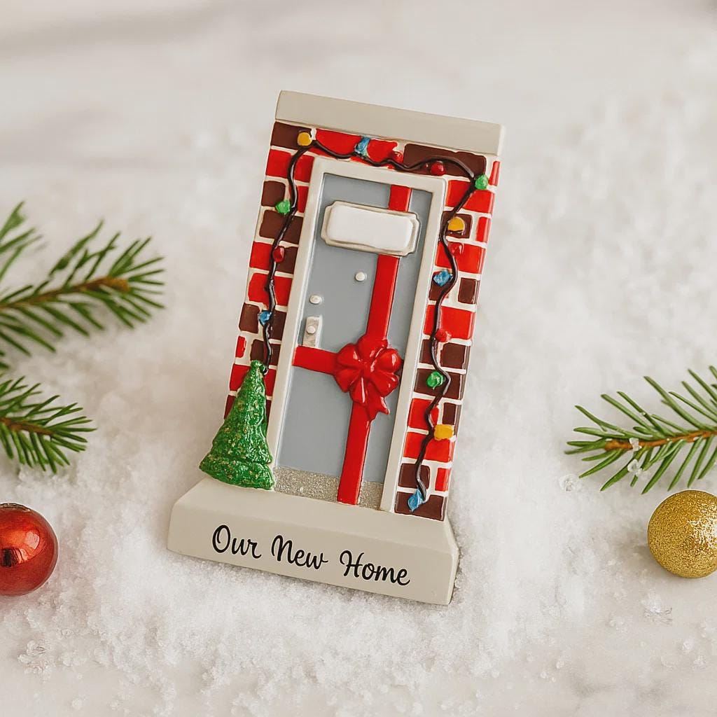 Decorative keychain with a house design and 'Our New Home' text, surrounded by Christmas decorations on a snowy background.
