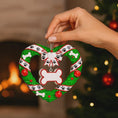 Load image into Gallery viewer, Heart-shaped Christmas ornament with a wreath design, held by a hand in front of a fireplace and tree.
