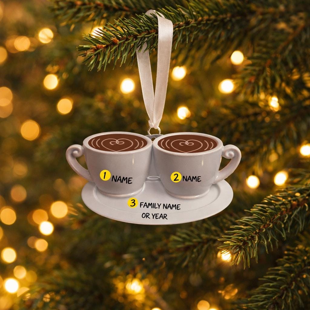 Decorative ornament with two coffee cups on a saucer against a Christmas tree background.