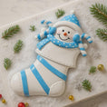 Load image into Gallery viewer, Decorative snowman ornament with blue accents on a snowy background with pine branches and ornaments.
