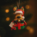 Load image into Gallery viewer, Christmas ornament of a reindeer with a gift and candy cane on a dark background with lights.
