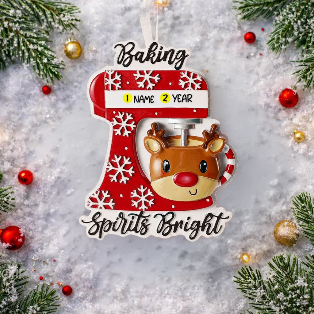 Personalized baking ornament featuring a festive red stand mixer design with snowflake details and a cute reindeer bowl accent. Finished with a smooth glossy surface and holiday inspired colors. Includes free handwritten personalization with one name and year displayed on the mixer. Designed with a raised 3D front and flat back for easy hanging. Styled in a cozy Christmas setting with snow greenery and ornaments, perfect for bakers home cooks and holiday keepsakes.