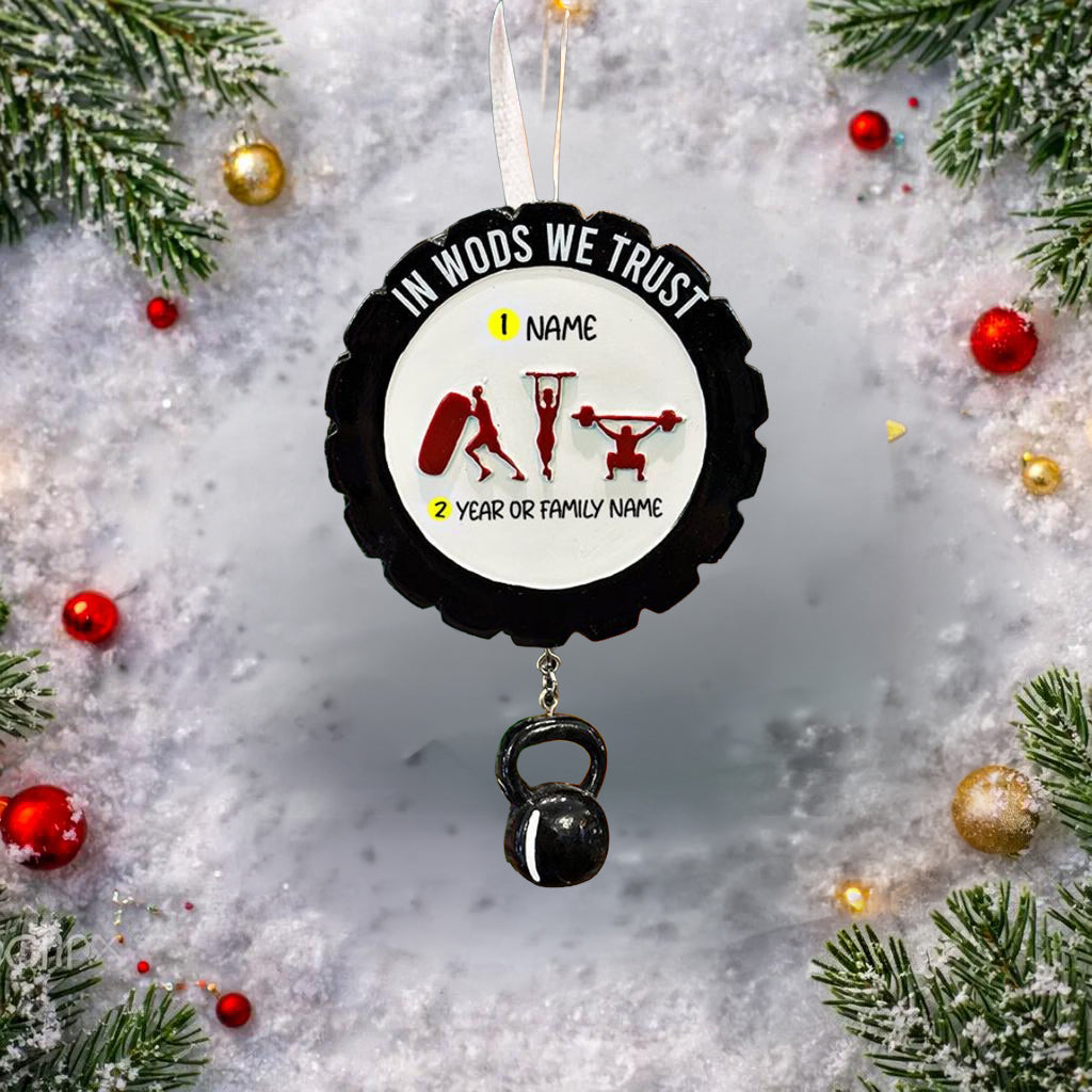 Personalized weightlifting and fitness Christmas ornament featuring a raised 3D front with bold circular design and red strength icons including boxing, gymnastics rings, and weightlifting. The ornament has a textured black outer rim and a flat 2D back for easy hanging. Includes a hanging kettlebell charm for added depth and movement. Hand-added personalization allows a name and year or family name. Photographed on a festive Christmas tree background with warm holiday lights.
