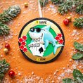 Load image into Gallery viewer, Personalized poker ornament featuring a cool shark character wearing sunglasses with playing cards and red casino chips. Designed in a round ornament style with a glossy finish. Includes free handwritten personalization with one name and year displayed on the front. Shown hanging with a ribbon in a festive holiday setting with greenery snow and seasonal decor. 3D raised front and flat back design perfect for Christmas trees and gifts for poker players casino lovers and card game fans.
