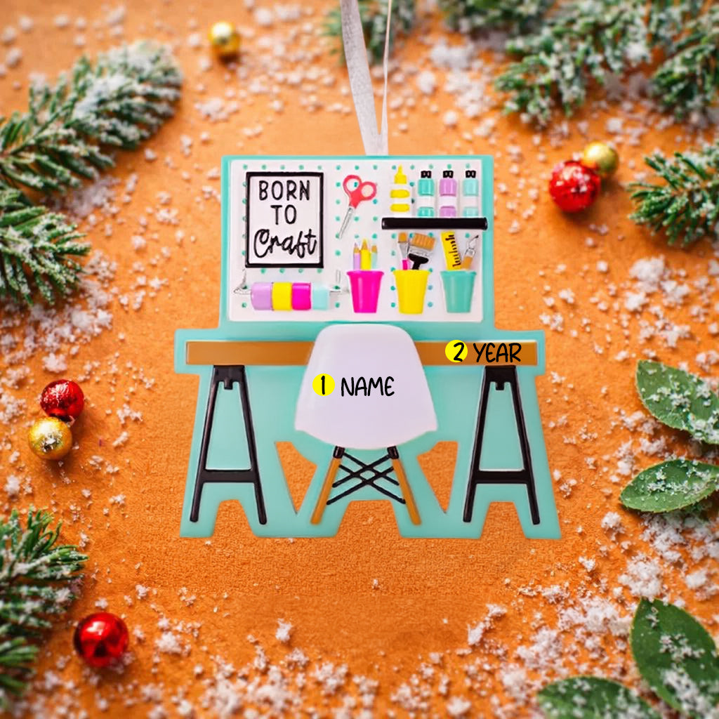 ornament featuring a creative desk scene with colorful craft supplies including scissors paint bottles brushes pencils and storage cups. The ornament showcases a playful crafting workspace design with a modern chair and desk setup. Made from durable resin with a detailed 3D front and flat 2D back for smooth hanging. Includes free handwritten