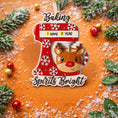 Load image into Gallery viewer, Personalized baking ornament featuring a festive red stand mixer design with snowflake details and a cute reindeer bowl accent. Finished with a smooth glossy surface and holiday inspired colors. Includes free handwritten personalization with one name and year displayed on the mixer. Designed with a raised 3D front and flat back for easy hanging. Styled in a cozy Christmas setting with snow greenery and ornaments, perfect for bakers home cooks and holiday keepsakes.
