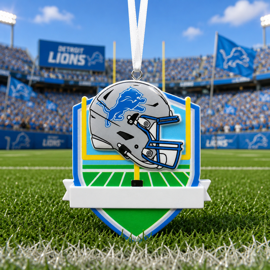 Detroit Lions themed shield-shaped ornament hanging on a football field, featuring a silver helmet with the blue lion logo, yellow goal posts, green turf, and a white hanging ribbon.