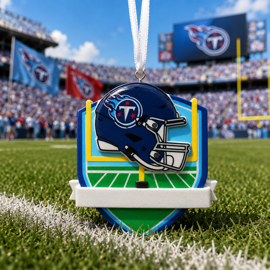 A Tennessee Titans football helmet ornament hanging from a white ribbon, displayed on a grassy football field with a blurred stadium background.