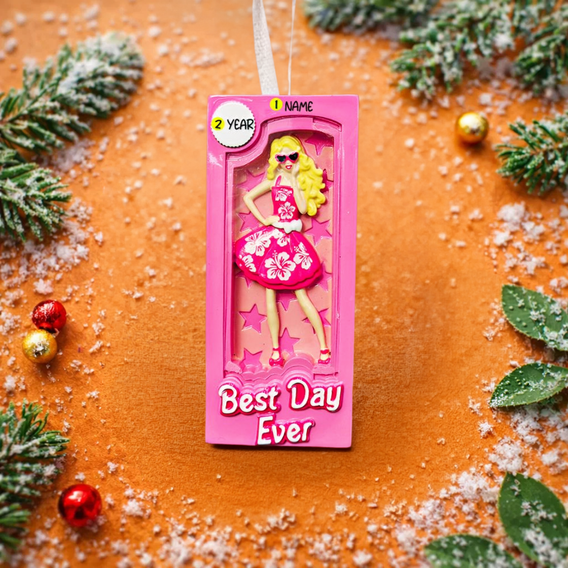 A vibrant pink fashion doll ornament with a retro camera-frame look and floral dress, perfect for holiday trees. Features bright colors, playful style, and a customizable area for adding a name or short text. Designed as a fun keepsake for kids and collectors who love bold, glamorous ornaments. Ideal for Christmas décor, stocking stuffers, and memorable seasonal gifting.